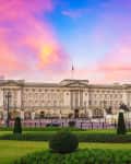 Buckingham Palace with Victoria Memorial in front, under a vibrant sunset sky.