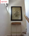 Stairway landing with a wicker table and framed botanical artwork on the wall.