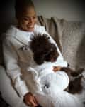 Person and brown dog in matching white robes with "TP&C" logo, sitting on a couch.