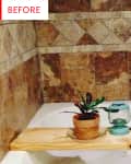 Bathtub with wooden board holding a potted plant and lantern, surrounded by brown tile walls.