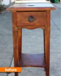 Worn wooden side table with a single drawer and lower shelf, set on a sidewalk.