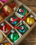 Box of colorful Christmas ornaments on a wooden table.