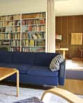Living room with blue sofa, wooden coffee table, bookshelf, and modern pendant light.