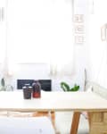 Bright room with a wooden table, yellow ladder shelf, potted plants, and wall art.