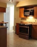 Kitchen with brown cabinets, granite countertops, stainless steel oven, and overhead microwave under track lighting.