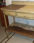 Worn yellow wooden side table with two drawers and a lower shelf, showing signs of distress and peeling paint.