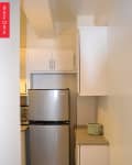 Narrow kitchen with stainless steel fridge, white cabinets, and a green pot on the counter.