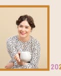 Smiling woman in polka dot dress holding a white mug, framed with text "Alexandra Gater" and "2020."