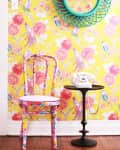 Fabric-covered chair in front of wallpapered wall
