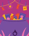Cauldron filled with colorful candy packets, surrounded by pink grass, with more candy hanging on a line above.