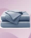 Folded blue bed sheets on a pastel pink abstract background.