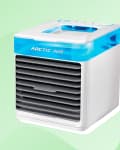 Compact Arctic Air cooler with blue top and black vents on a green background.
