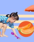 Child in striped shirt playing with sand toys, orange bucket, and slices of cantaloupe under a red umbrella.