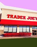 Trader Joe's storefront with red awning, shopping carts lined up outside, and a person entering.