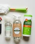 Cleaning supplies including a duster, cloth, brushes, window cleaner, all-purpose cleaner, and disinfecting wipes.