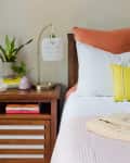 Wooden nightstand and wooden bed with simple decor and accent colors