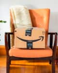Amazon Prime package on an orange chair with a plant and magazine rack nearby.