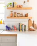Organized white kitchen with wooden shelving and decor.
