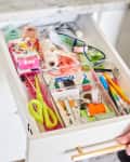 Open kitchen drawer with organized office supplies, including scissors, pens, tape, and band-aids.