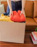 cardboard box with someone putting clothes in on coffee table