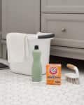 Cleaning supplies on hexagonal tile floor, including a mop, bucket, baking soda, scrub brush, and towel.