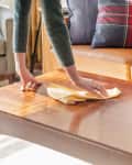 Wiping down coffee table with dusting cloth
