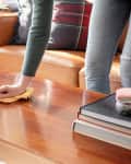 Wiping down coffee table with dusting cloth