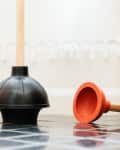 A toilet plunger and sink plunger in the bathroom