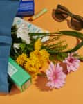 Tote bag with flowers, sunglasses, receipt, wallet and coffee cup on a gold background