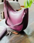 Purple purse, light purple wallet, keys on a dining room table