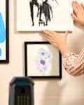 head on shot of someone installing a gallery wall, using a laser level
