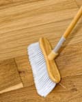 angled shot of someone sweeping up a hardwood floor