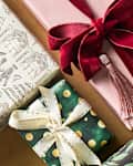 Colorful wrapped gifts with various ribbons and decorative elements on a wooden surface.