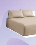 Beige bed with matching pillows on a purple abstract background.