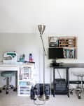 Home office with sewing machine, desk, computer, bookshelves, and a floor lamp in a small room.