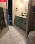 Bathroom with white tile floor, light blue vanity, granite countertop, and towel hanging on the wall.