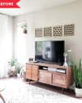 Living room with a wooden TV stand, potted plants, and geometric wall art above the television.