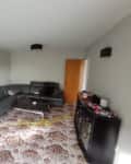 Living room with gray sectional sofa, patterned carpet, dark cabinet with toy cars, and a "Before" label in the corner.
