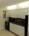 Before: kitchen with white cabinets, dark granite counters, and black appliances