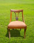 Before: A vintage wooden chair with cutout swayed back, sitting in a grassy backyard.