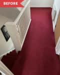 Hallway with red carpet, white railing, and a wall-mounted radiator.