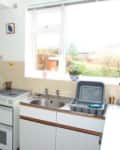Before: Dated kitchen with white cabinets and tan tile