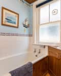 Before: Bathroom with natural wood vanity, blue walls, and nautical decor