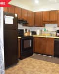 Before: Dated kitchen with crown cabinets, black appliances, and beige walls