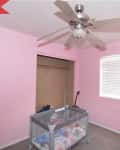 Before: bright pink bedroom with play pen and dated ceiling fan