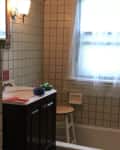 Before: Bathroom with white square tile and red paint on the walls, plus dark wood vanity