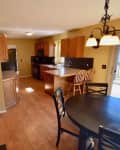 Kitchen with wooden cabinets, round dining table, chairs, and sliding glass door leading to a deck.