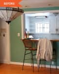 Kitchen pass-through with wooden counter, two wicker bar stools, teal walls, and a hanging stained glass light fixture.