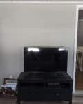 Before: Blank gray wall with a tv on a black TV stand sitting in front of it