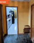 Hallway with yellow walls, wooden doors, a small wooden chair, and view into a kitchen with white cabinets and black fridge.